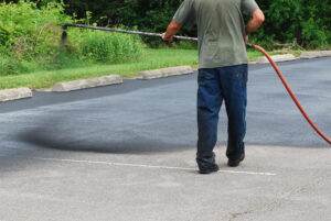 Spraying new sealer coat on an asphalt parking lot.