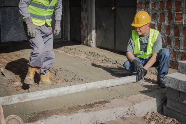 Worker leveling uneven concrete surface for smooth and durable finish